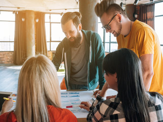 Creative millennial business group. Team leader communicating deadlines and sales goals to colleagues in modern openspace office.