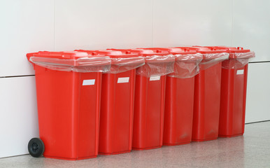 Six red plastic bins  on wheels 
