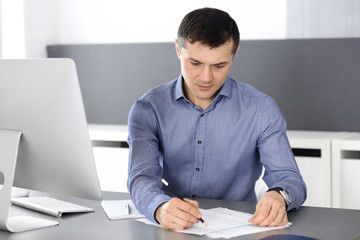 Fototapeta premium Businessman working with computer in modern office. Headshot of male entrepreneur or company director at workplace. Business concept