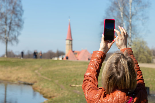 young girl takes a picture of a monument on a smartphone close-up