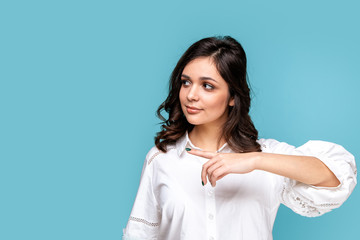Obraz premium Pretty brunette girl pointing something by finger isolated over the blue background