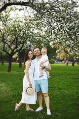 Beautiful young parents and their cute little son have fun near flowering trees, happy family