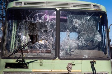 Bus glasses are heavily broken after car crashes on the road. The windows crashed when colliding at high speed.