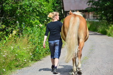 Woman walking on the country road with horse