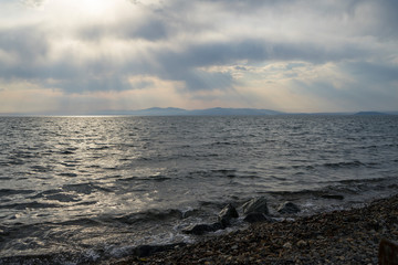 Shafts of sunlight shining through clouds to sea