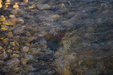 pebble stones on the sea beach, the rolling waves of the sea with foam