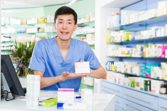  japanese specialist standing near table with cashbox in pharmacy