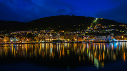 Night panorama of Bergen harbour with old buildings part of Bryggen district reflected in the water, Norway