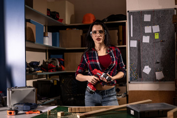 Woman with a drill screwdriver working in the workshop Studio alone