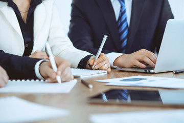 Group of businesspeople or lawyers discussing contract papers and financial figures while sitting at the table. Close-up of human hands at meeting or negotiations. Success and communication concept