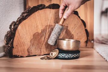 Bronze singing bowl with felt clapper on wooden ground for meditation or massage