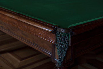 angle expensive billiard table corner pocket. pocket with mesh for the sword. the table is on the floor.