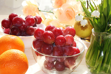 Juicy red grapes, pears and oranges on a light background with drops close-up, tasty, dietary and healthy food for a healthy lifestyle.