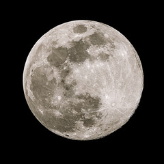 A full moon isolated against a black night sky in high resolution with fine details on the surface