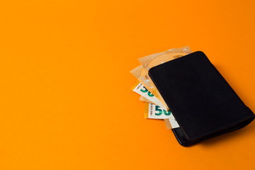 black wallet with euro money on a yellow background
