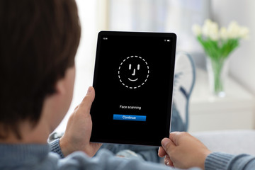 man hands holding computer tablet with face ID scanning