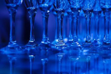 Close-up of coupe glasses with reflections in blue light on blurred background