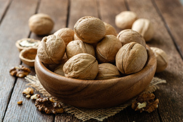 Walnuts in wooden bowl on rustic background. Selective focus.