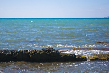 rocky sea shore with pebble beach, waves with foam