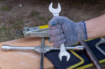 Obraz premium Male hand in glove with the wrench in the background is the Jack and wheel brace