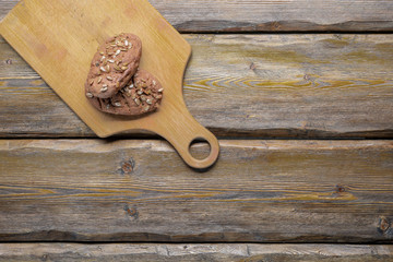 whole wheat bread with sunflower seeds and knife with cutting board and burlap on wooden background, top view 