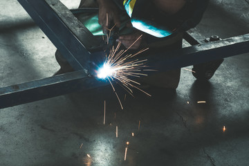Worker welding steel frame with MIG technology