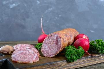Homemade kraft sausage salami, sliced on a wooden board.