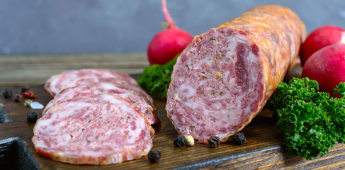 Homemade kraft sausage salami, sliced on a wooden board.