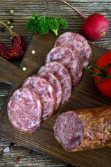 Homemade kraft sausage salami, sliced on a wooden board.