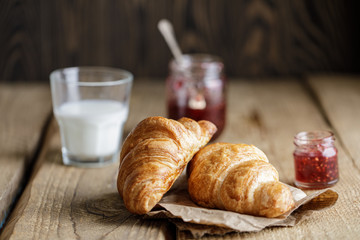Freshly baked croissants with jam on wooden rustic background. Tasty croissants with copy space