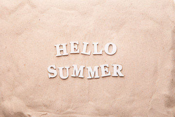 Text Hello Summer from white letters on sand.