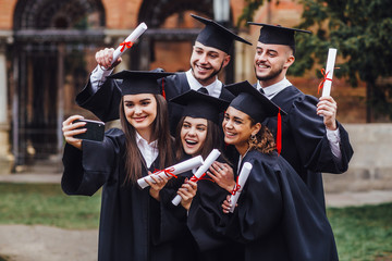 Portrait of multiracial graduates holding diploma and doing selfie on phone! Lifestule!