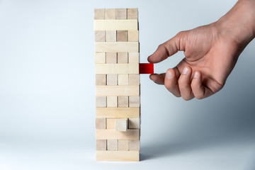 Male hand puts a cube on the tower of wooden cubes, as a symbol of support, teamwork and business...