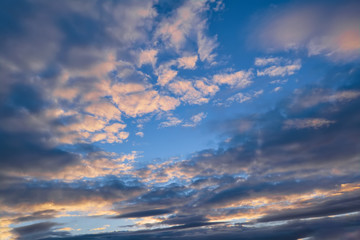 Blue sky with gold clouds - dramatic sunset, beautiful natural background. Setting sun illuminates the clouds.