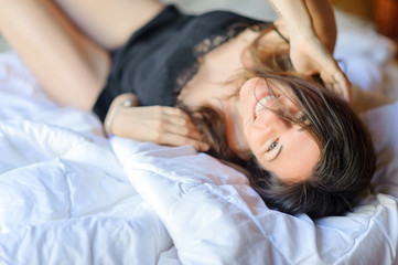Fototapeta premium young beautiful girl in lingerie is resting in her bed and smiling