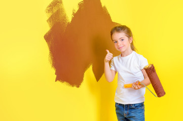 funny little girl with paint roller smiling and shows class near painted wall. Repair in the apartment.