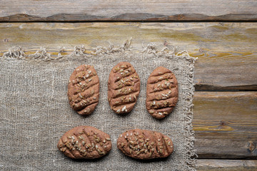 whole wheat bread with sunflower seeds and knife with cutting board on wooden background, top view  