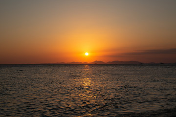 Beautiful golden sunset by the sea and the mountains. View from phra nang beach. Krabi