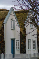 Scenic landscape view of tourist popular attraction/destination historical traditional Grenjadarstadur farm houses with turf roof, a church and cemetery nearby. Lake Myvatn, Iceland