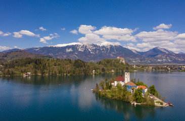 Fototapeta na wymiar Bled, Slovenia - 04 19 2019: Lake Bed in Slovenia with Alps covered with snow in the background.