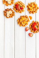 Traditional belgian waffles with fruit topings on white wooden background top view mock up