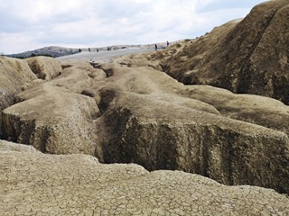 Arid landscape created by the Mud Volcanoes in Berca, Romania. A mud volcano or mud dome is a landform created by the eruption of mud or slurries, water and gases