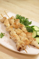 Baked chicken fillet on wooden skewers with cucumber and dill.