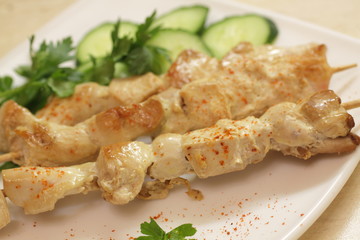 Baked chicken fillet on wooden skewers with cucumber and dill.