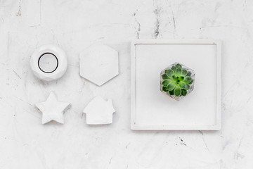 modern design of work desk with plant, candle, house and star figures on white marble background top view