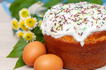 Easter cake and colored eggs yellow flower blossoms on background. Holiday food and easter concept. Selective focus. Copyspase