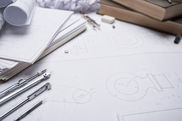 Architectural prints and print rolls and a drawing instruments on the worktable.