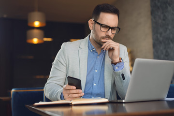 Worried businessman having problems while working on a computer in a cafe