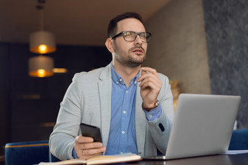 Young businessman thinking of new business ideas and looking away in the office