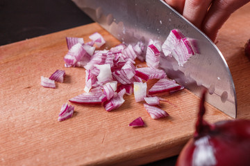young woman in a gray aprons cuts red onion